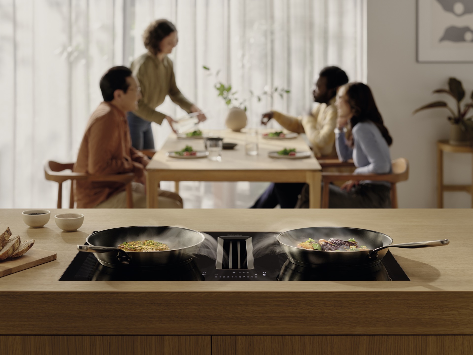 Placa inducción Miele con extracción integrada isla madera comedor familia cocción