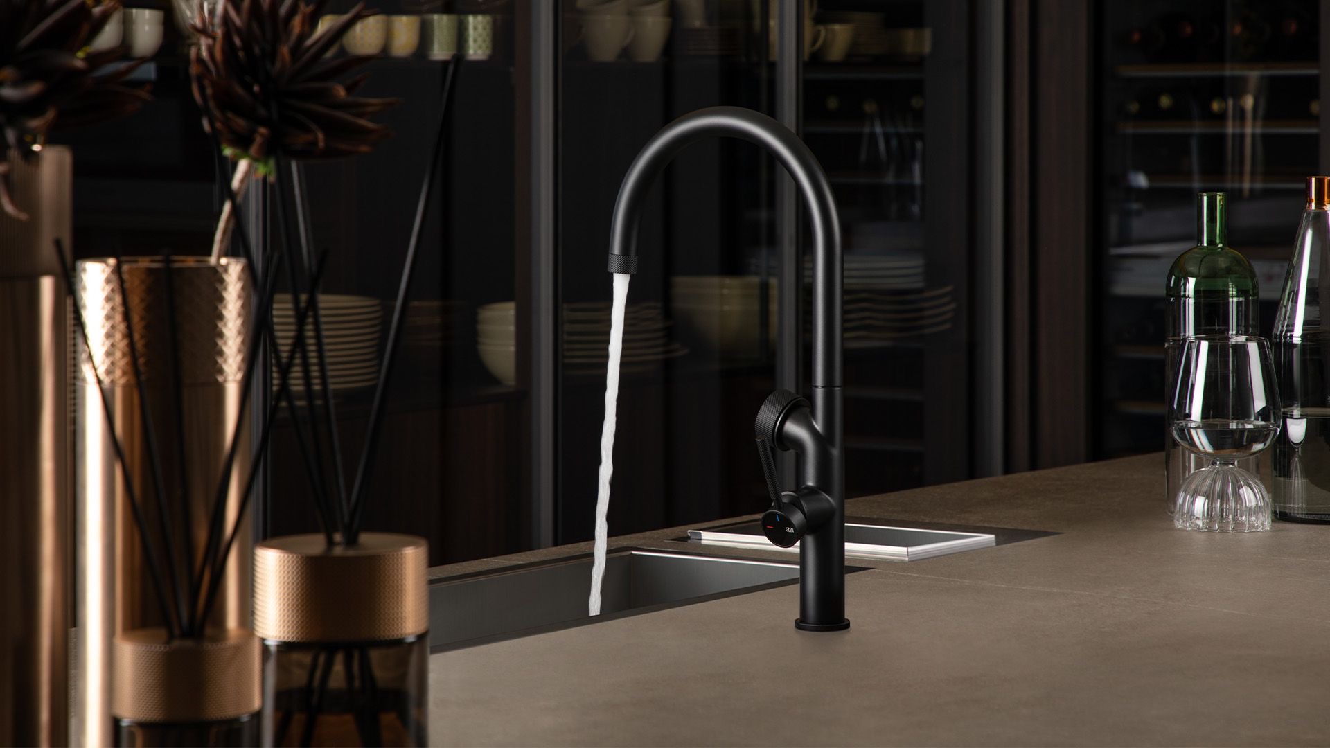 Gessi Vita tap in matt black on a stone worktop with an integrated sink in a contemporary kitchen