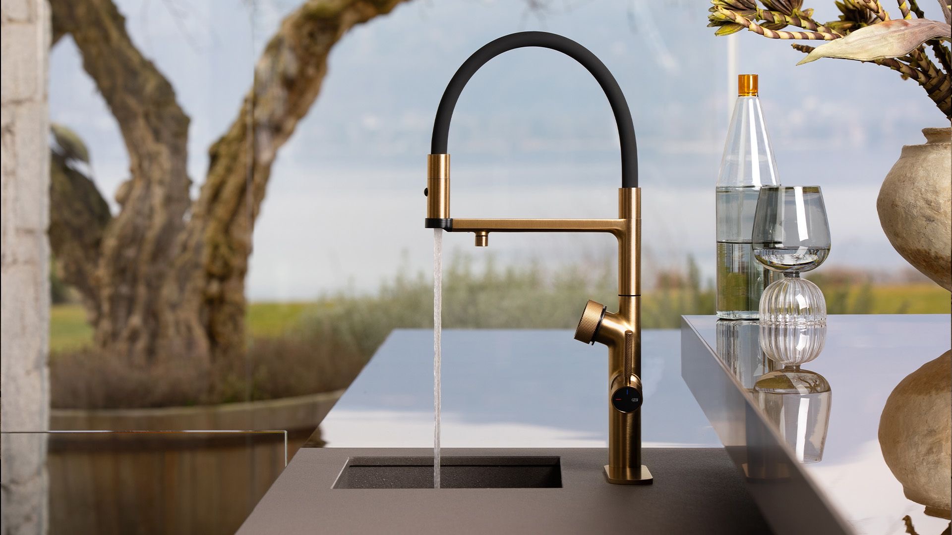 Gessi Vita tap on a worktop beside a bottle and a glass of water, an alternative to bottled water