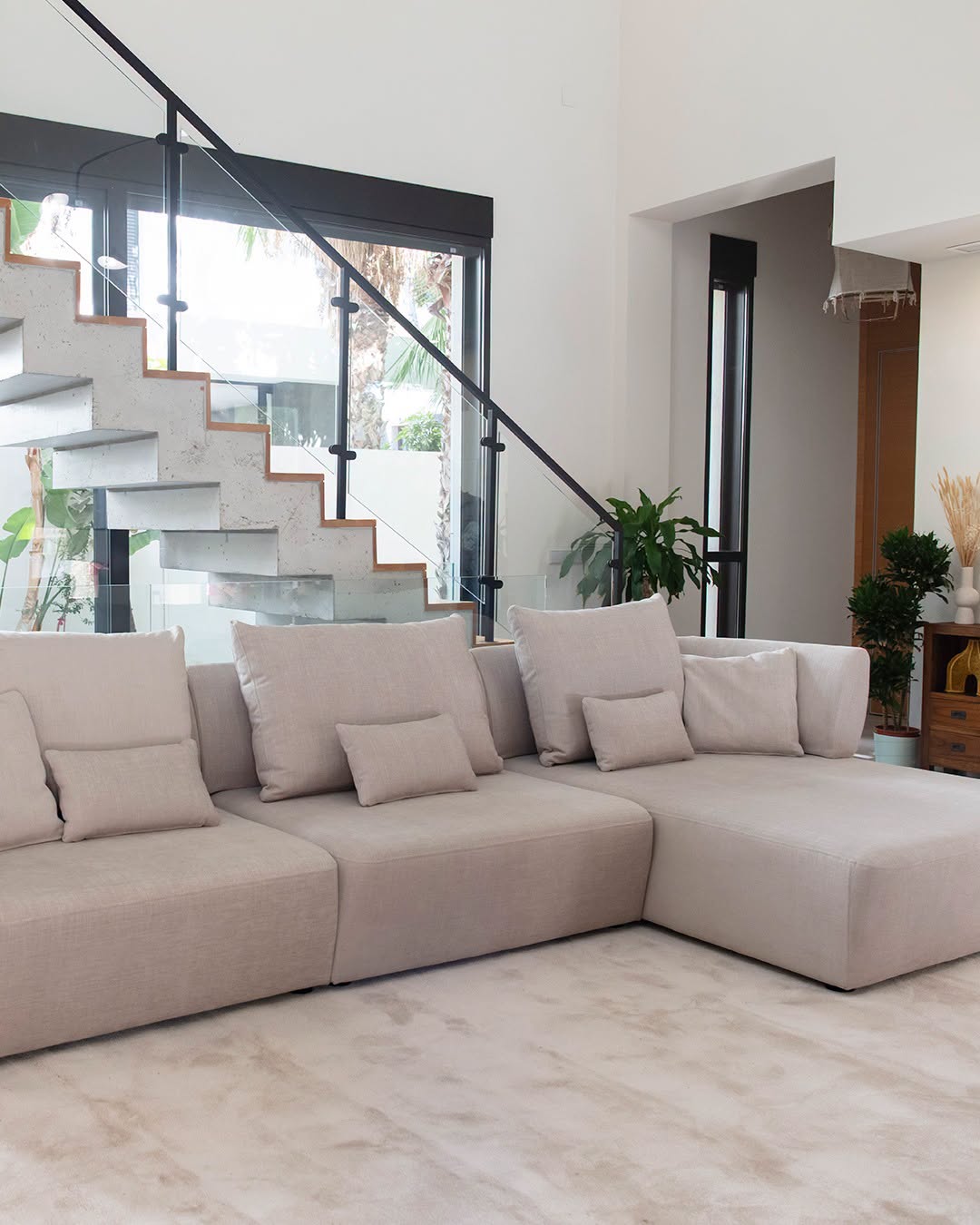 Beige linen Fama modular sofa with chaise longue module in a double-height living room