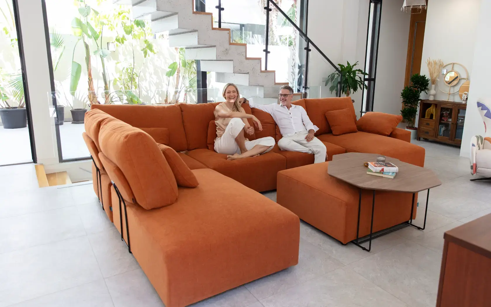 Fama Teseo sofa in a corner composition upholstered in terracotta orange with pouf and coffee table