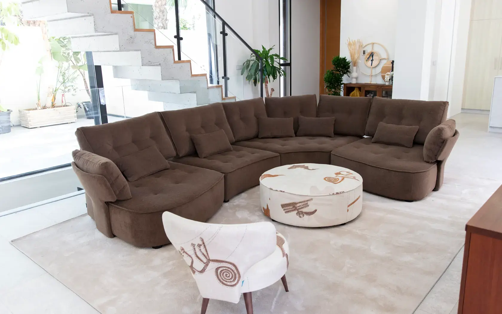 Fama Arianne Love sofa in a curved composition upholstered in chocolate brown with a round pouf